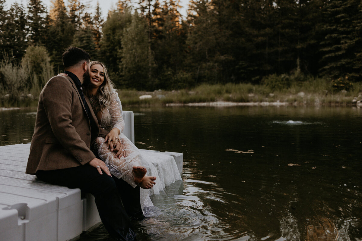bride and groom on a dock laughing and holding each other