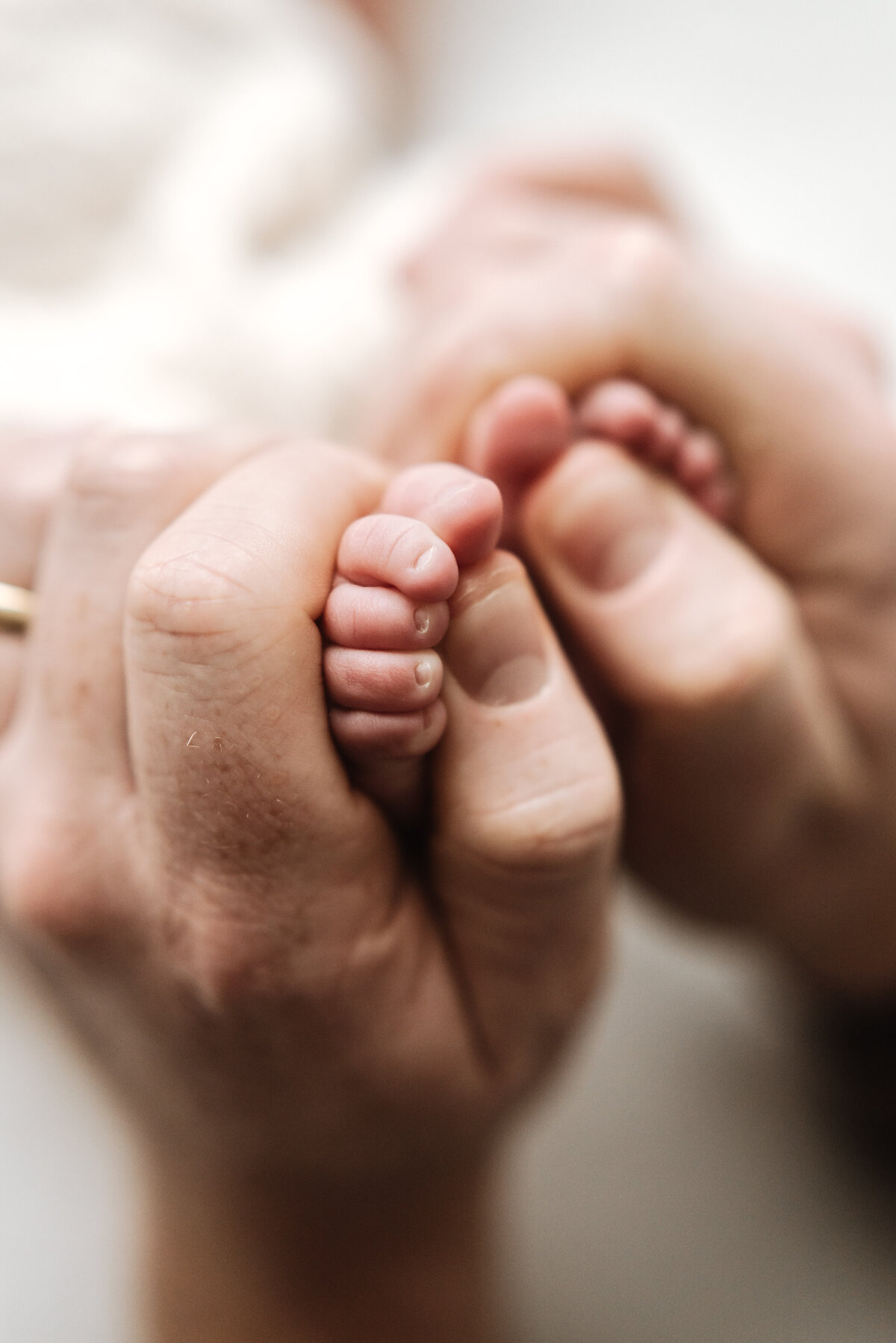 Man holding babies toes in his hands at newborn photoshoot in Billingshurst