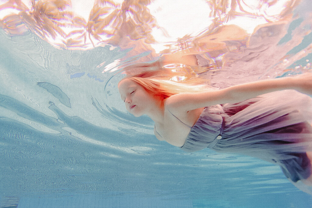 little girl in dress swimming underwater