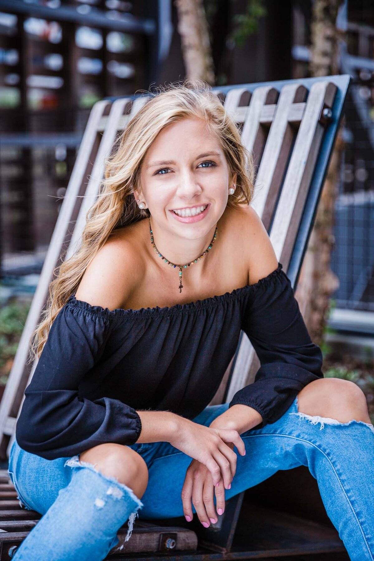 A smiling fun senior portrait of a beautiful blonde haired girl.