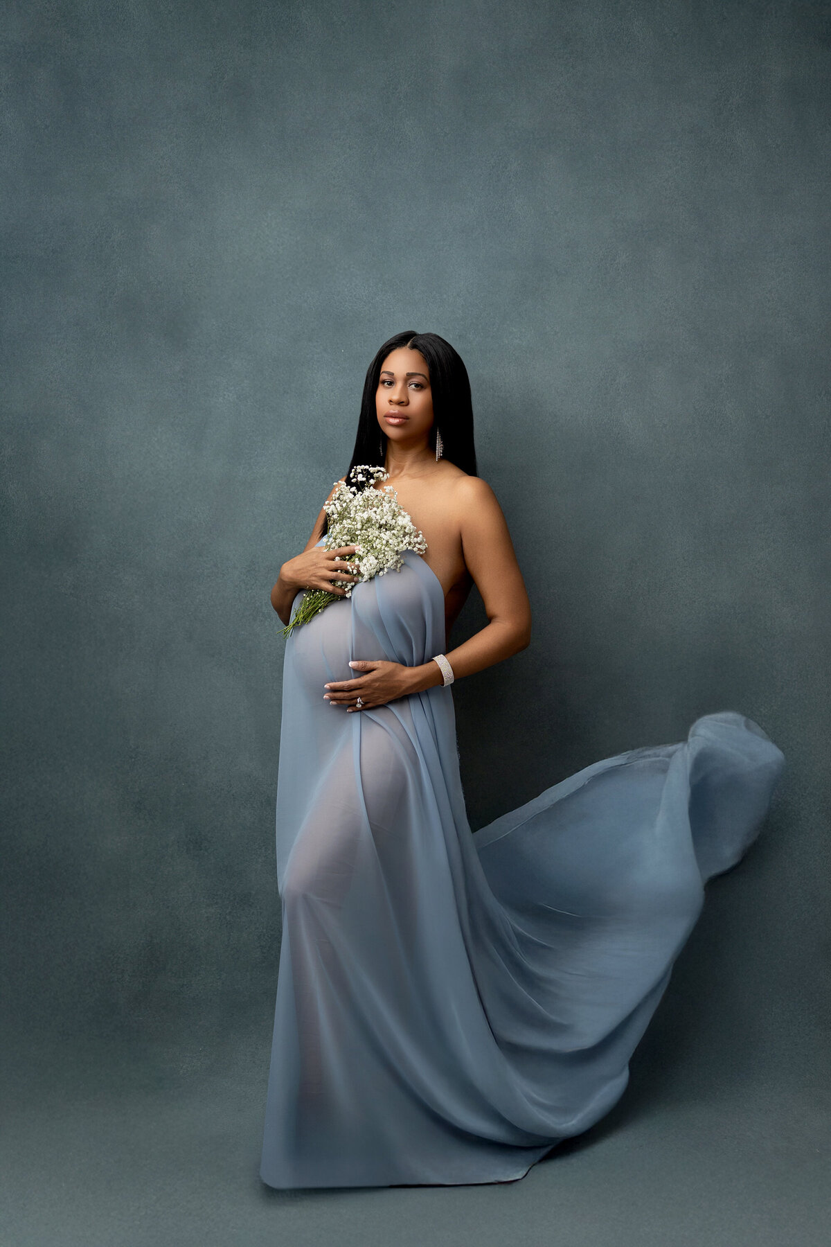 black pregnant woman posing on blue backdrop for maternity photographer in phoenix