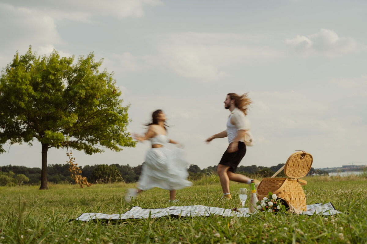 A fun and carefree capture of a couple running on the grass, embodying joy and spontaneity at White Rock Lake park.