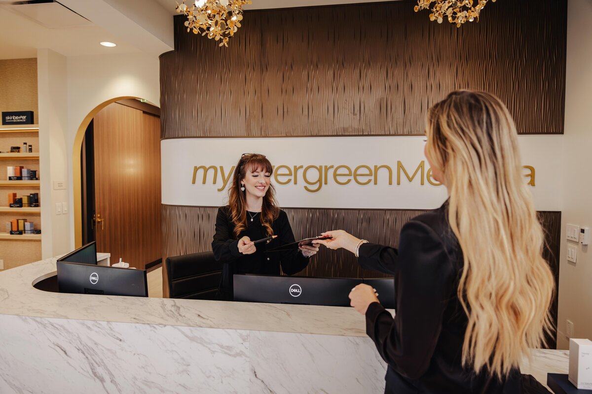 A patient booking a consultation with staff at a medspa front desk