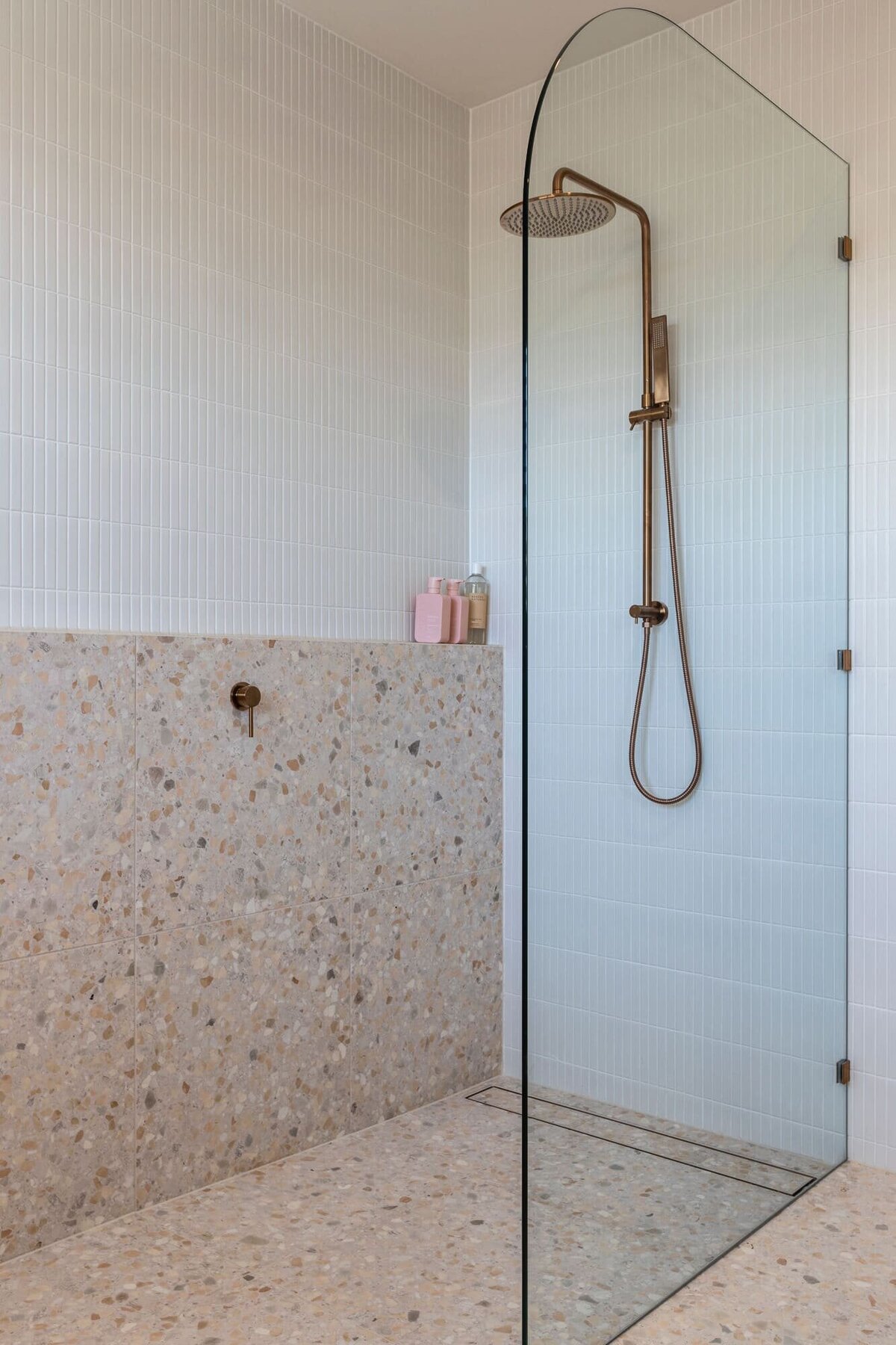 Pink terrazo tile shower with brass tap ware