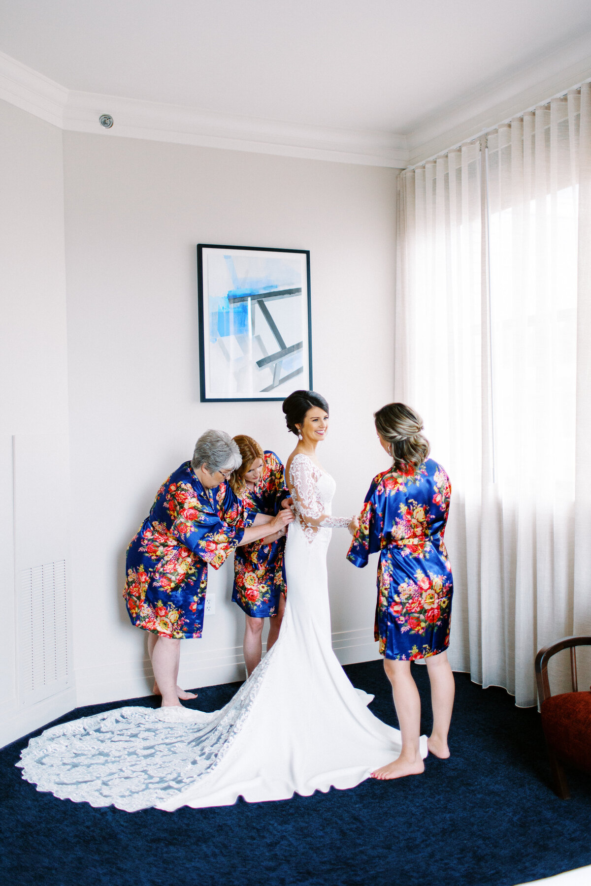 Mother and bridesmaids helping the bride with her dress