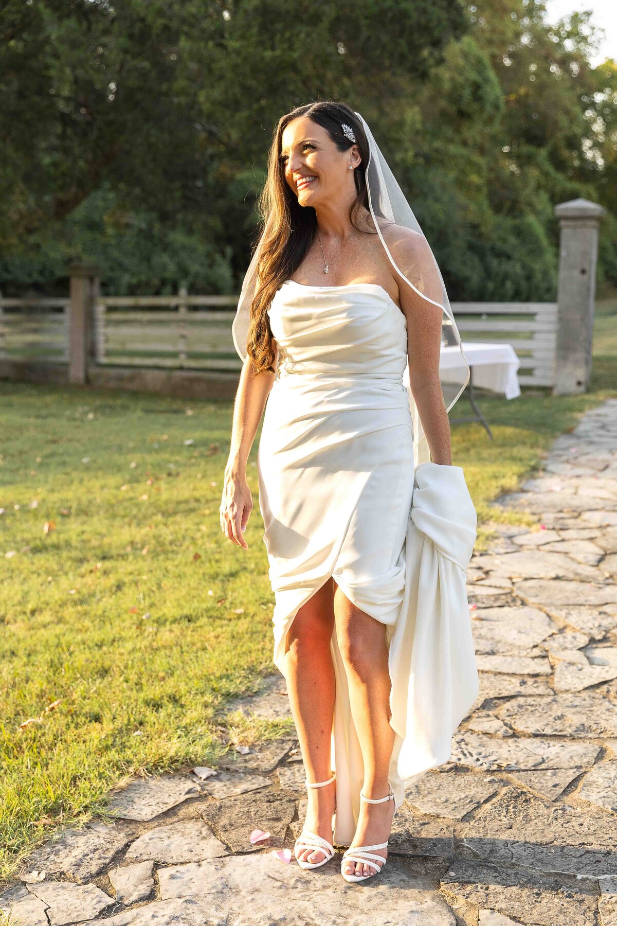 Bride holding wedding dress smiling into distance