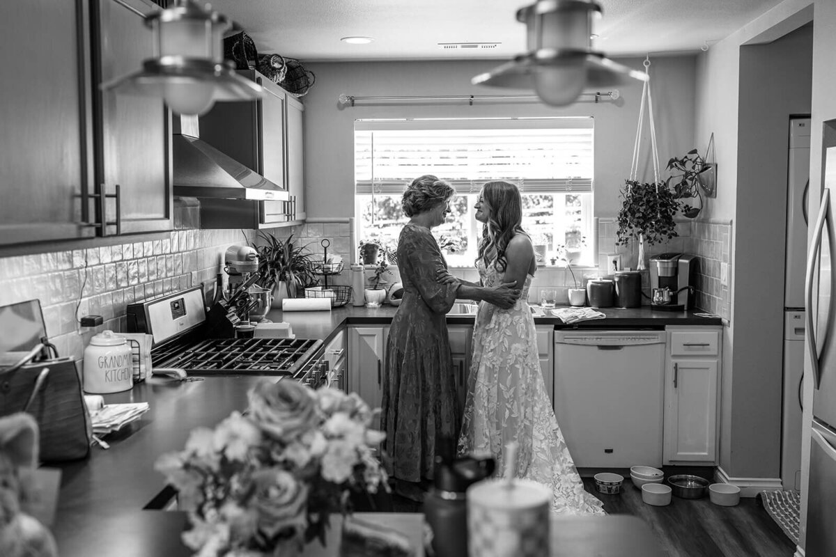 Two women embrace in kitchen.