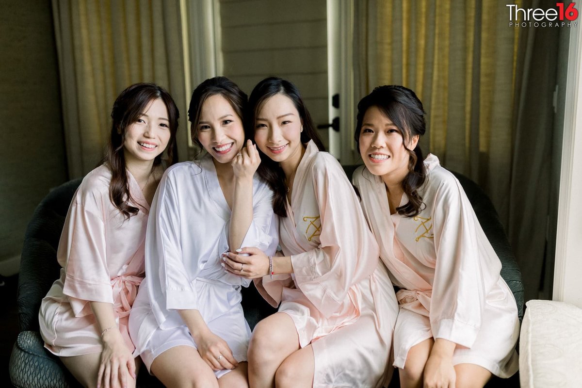 Bride and Bridesmaids pose together in their robes before getting dressed