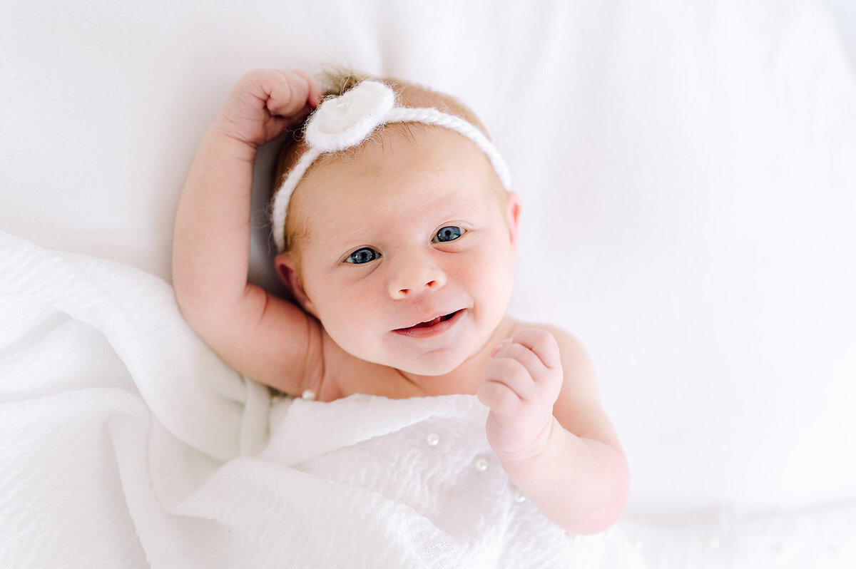 newborn-girl-wearing-white-headband-smiling