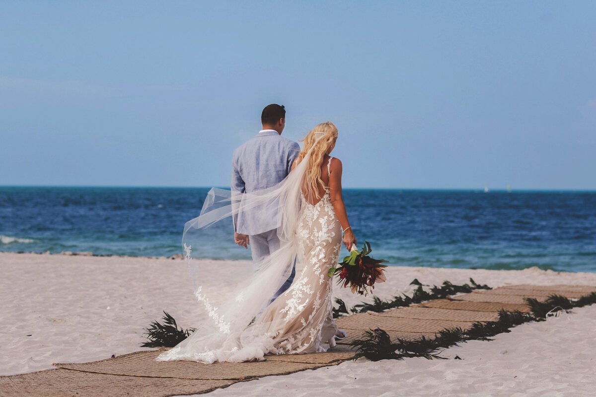 Bride and groom walk down aisle on beach in Cancun