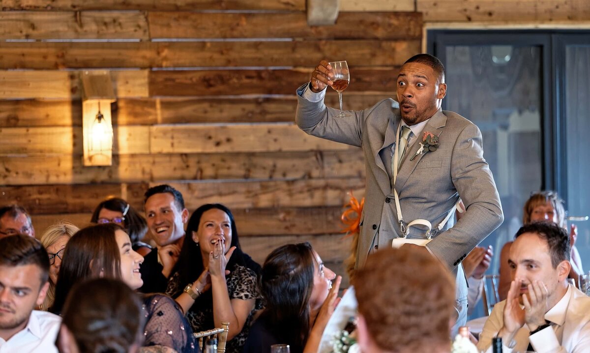 Groomsman pulling funny face while wedding guests laugh at him