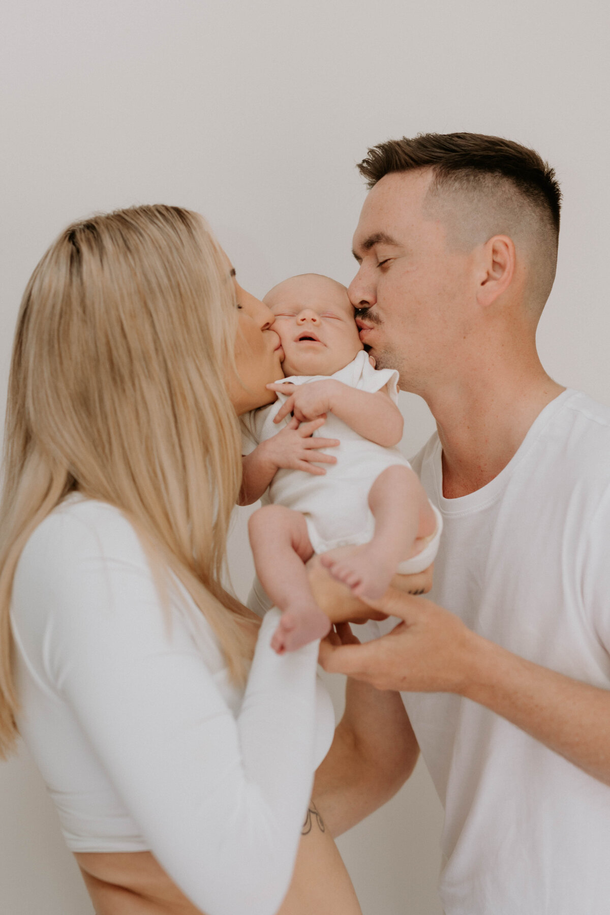 Mother and father kissing new baby