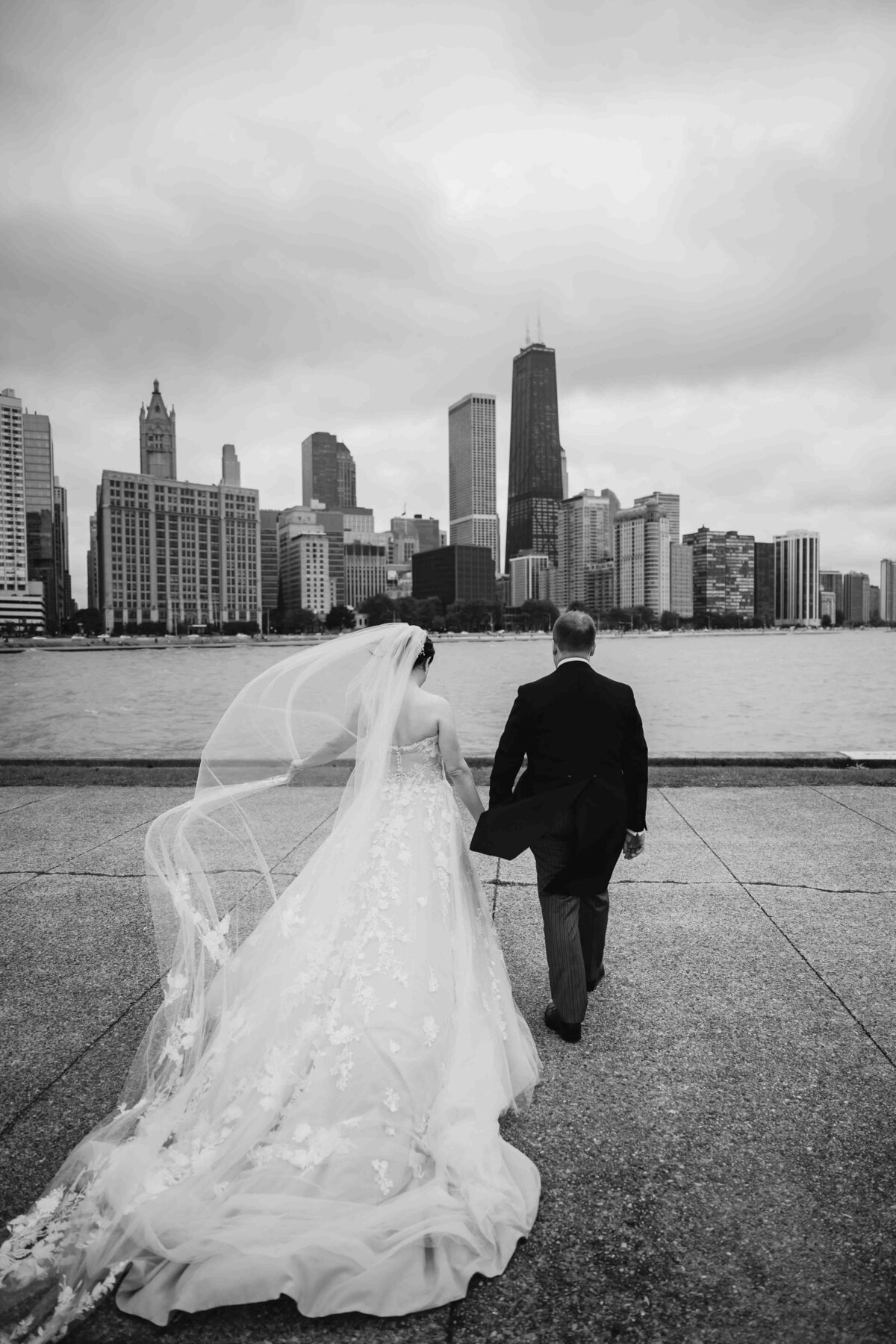 Bride and groom wallk towards Chicago skyline at Milton Lee Olive Park 