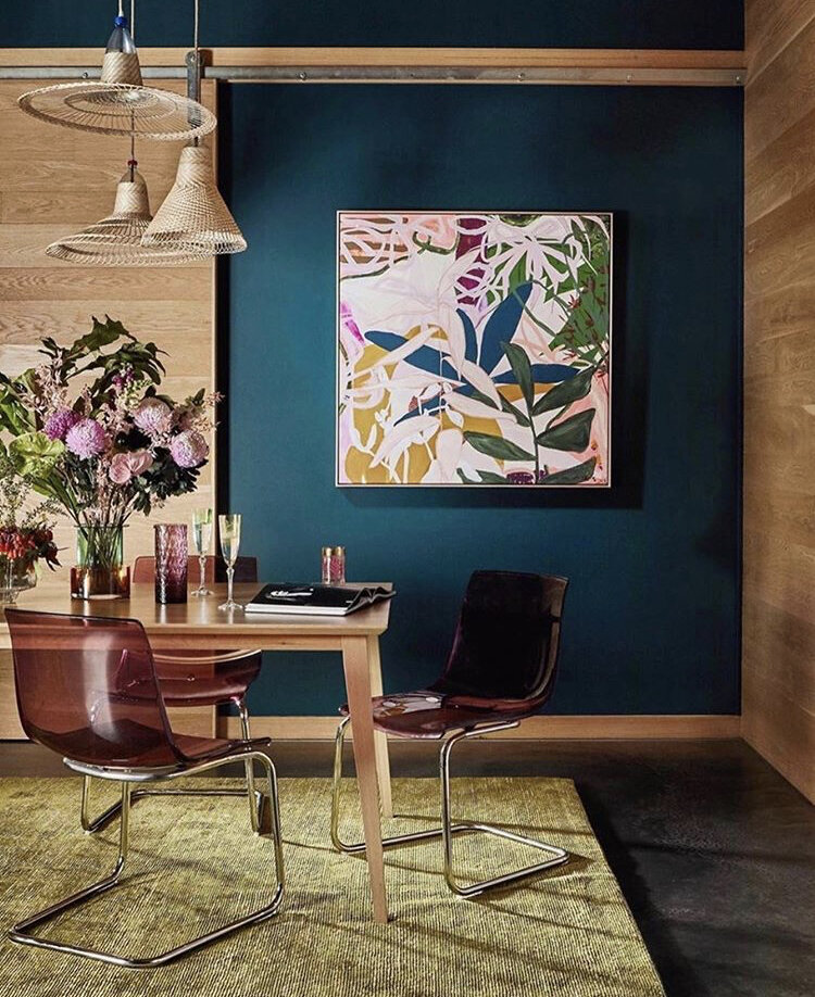 Lush botanical artwork above bed with layered bedding in vibrant blue and green – interior design Melbourne