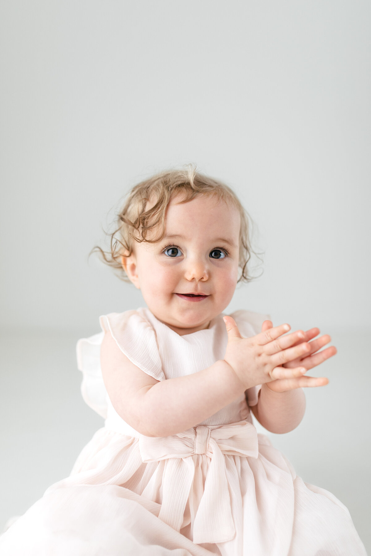 One year old girl claps her hands during her photoshoot