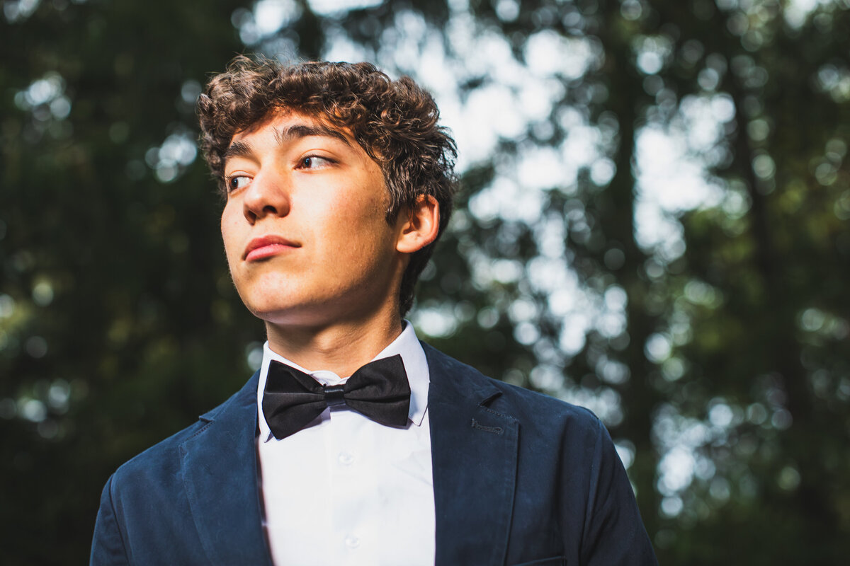 Dark haired boy poses with his sharp bowtie in the woods near Pittsburgh Pennsylvania only senior photography studio