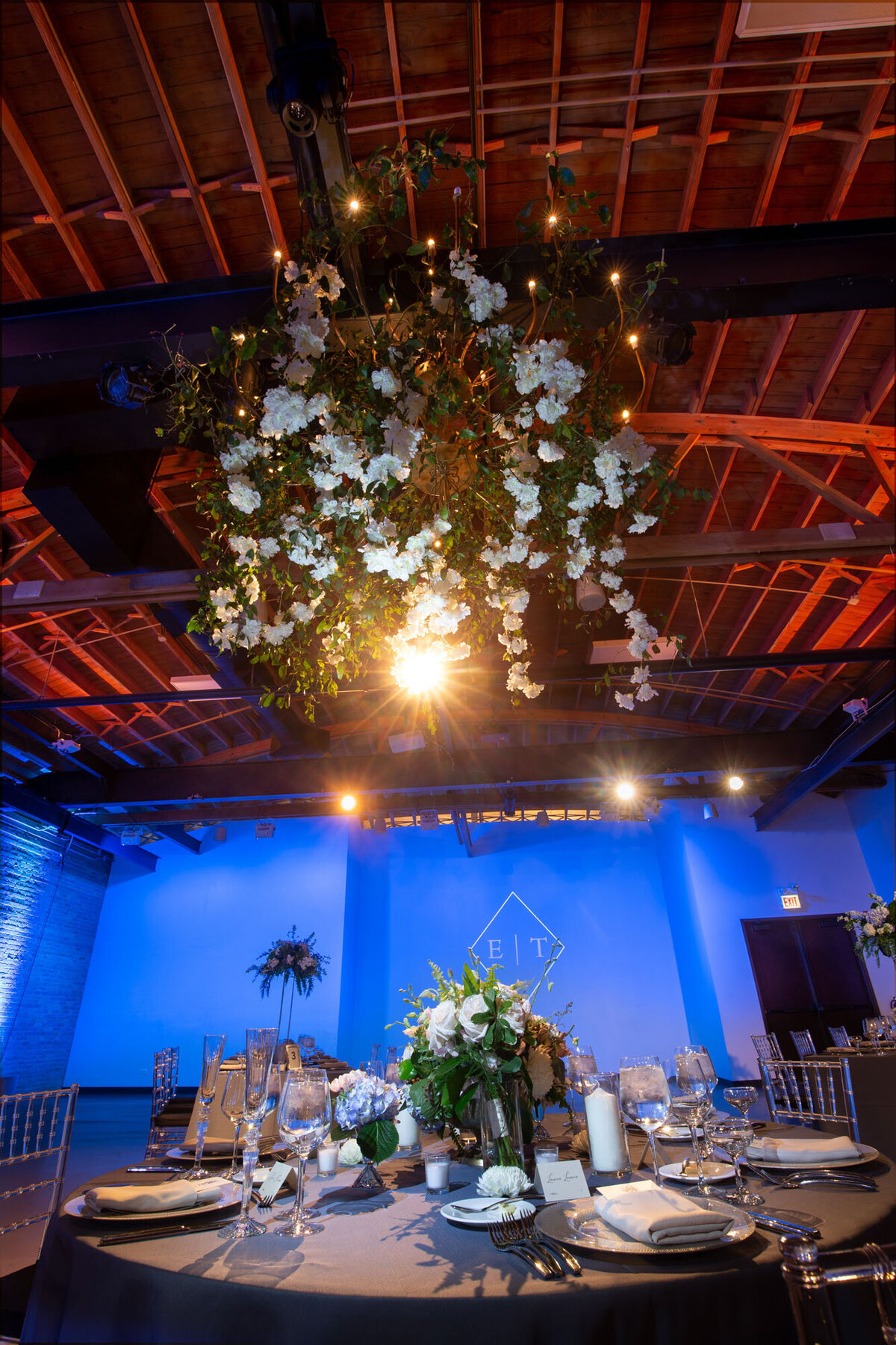 A large room with tables and chairs and flowers hanging from the ceiling