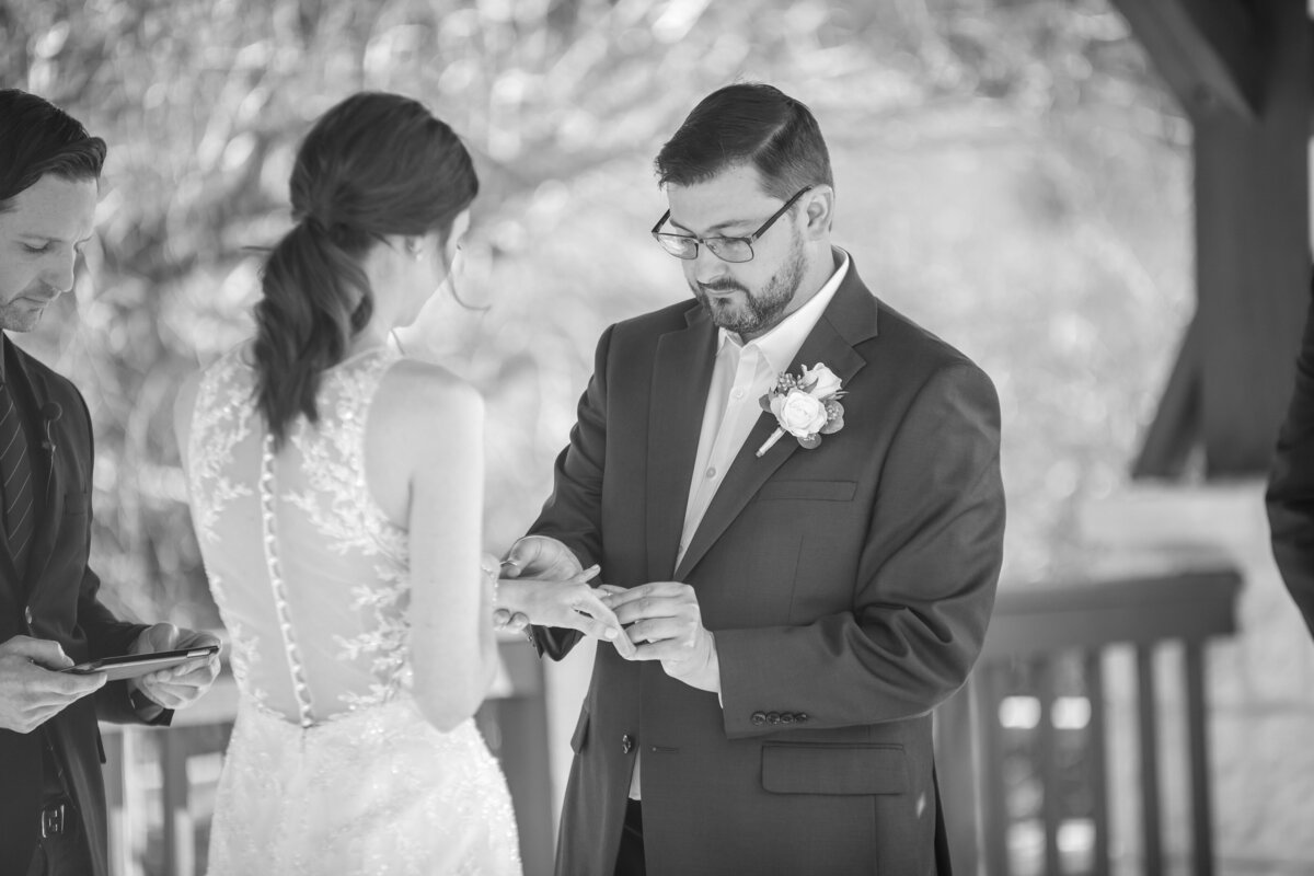 wedding photographer in texas captures black and white image of. groom placing ring on bride's hand in Boerne Texas