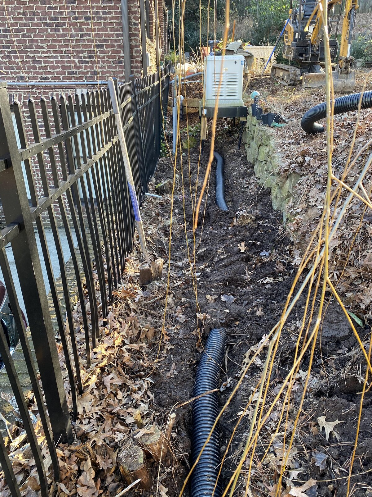 black-drainage-hose-in-dirt-next-to-metal-fence