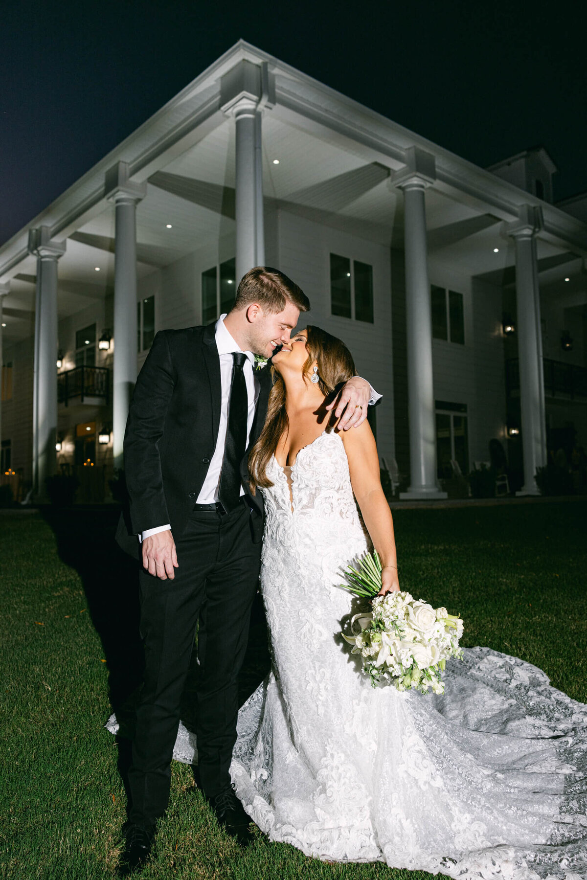 A wedding photo of the bride and groom in front of their wedding venue legacy acres