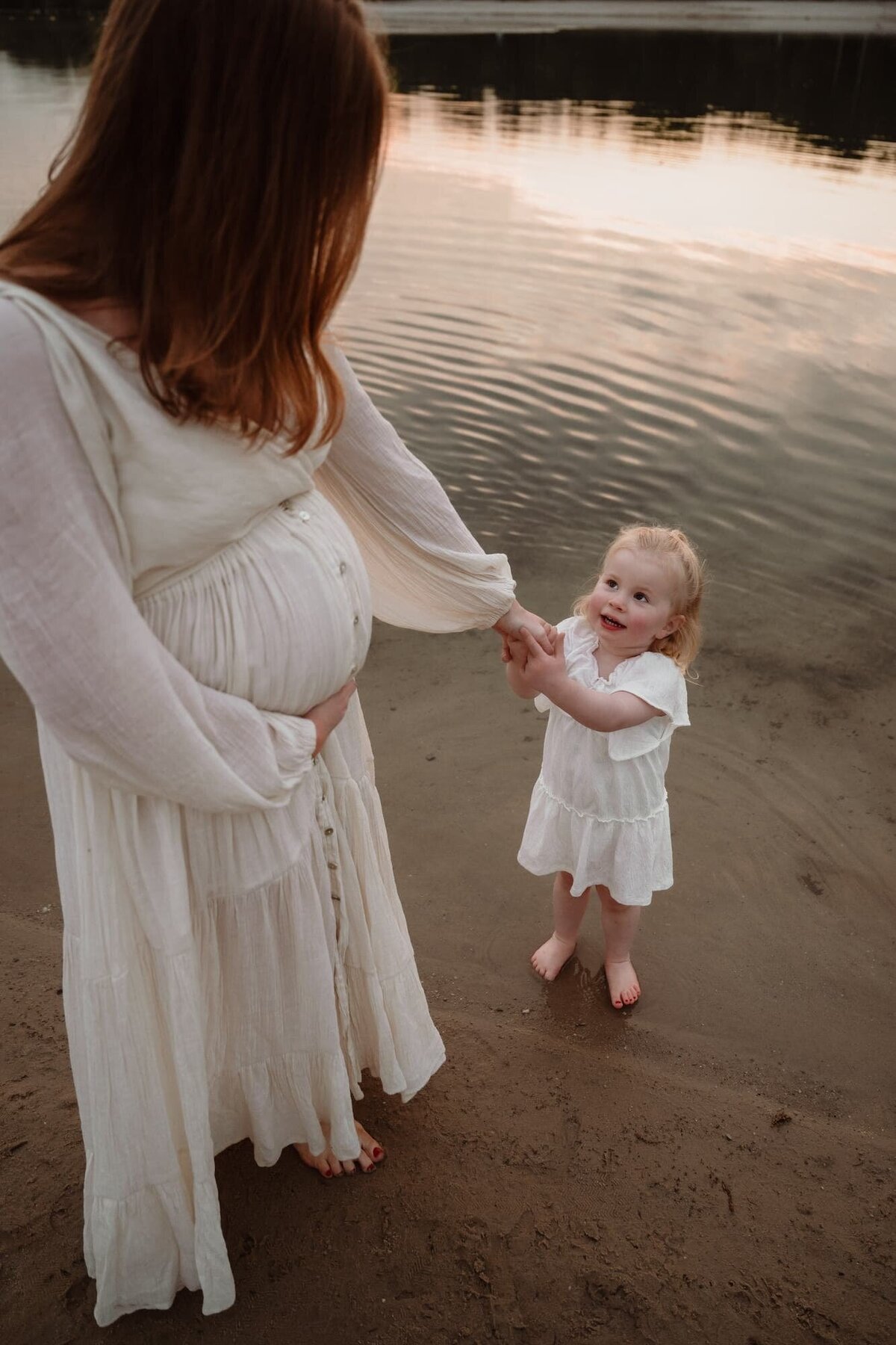 Mama en dochter tijdens zwangerschapsshoot aan plassen