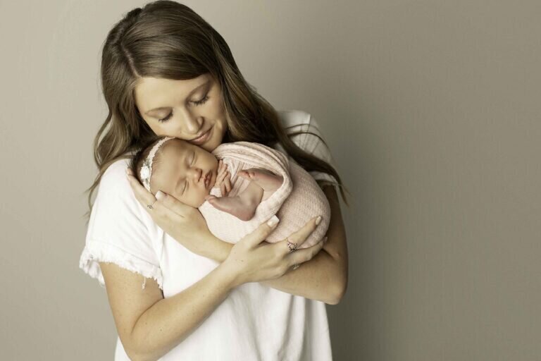 Mom gently cradling her newborn baby girl close to her chest, eyes closed, sharing a tender and intimate moment filled with love and warmth