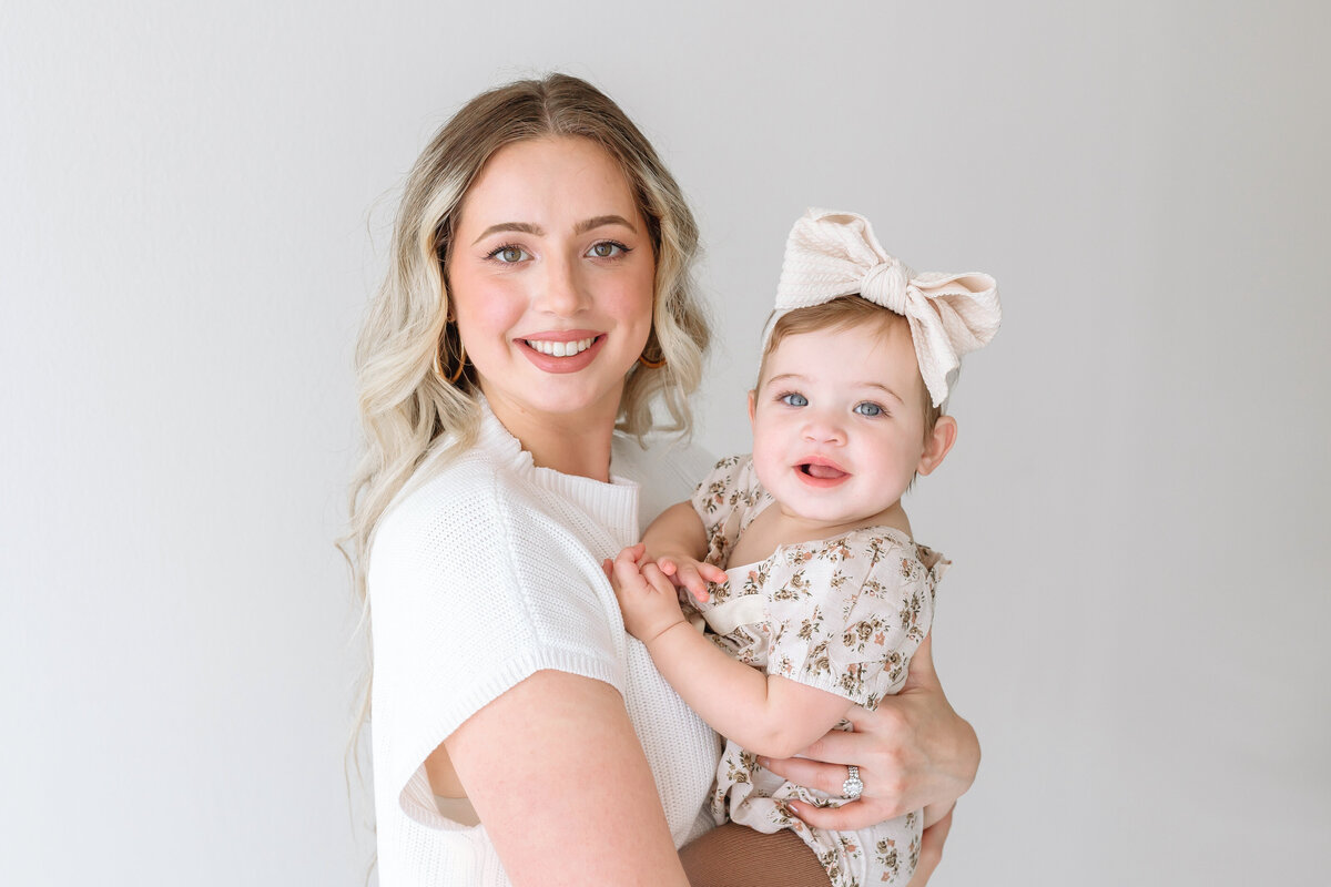 mom holding smiling toddler girl
