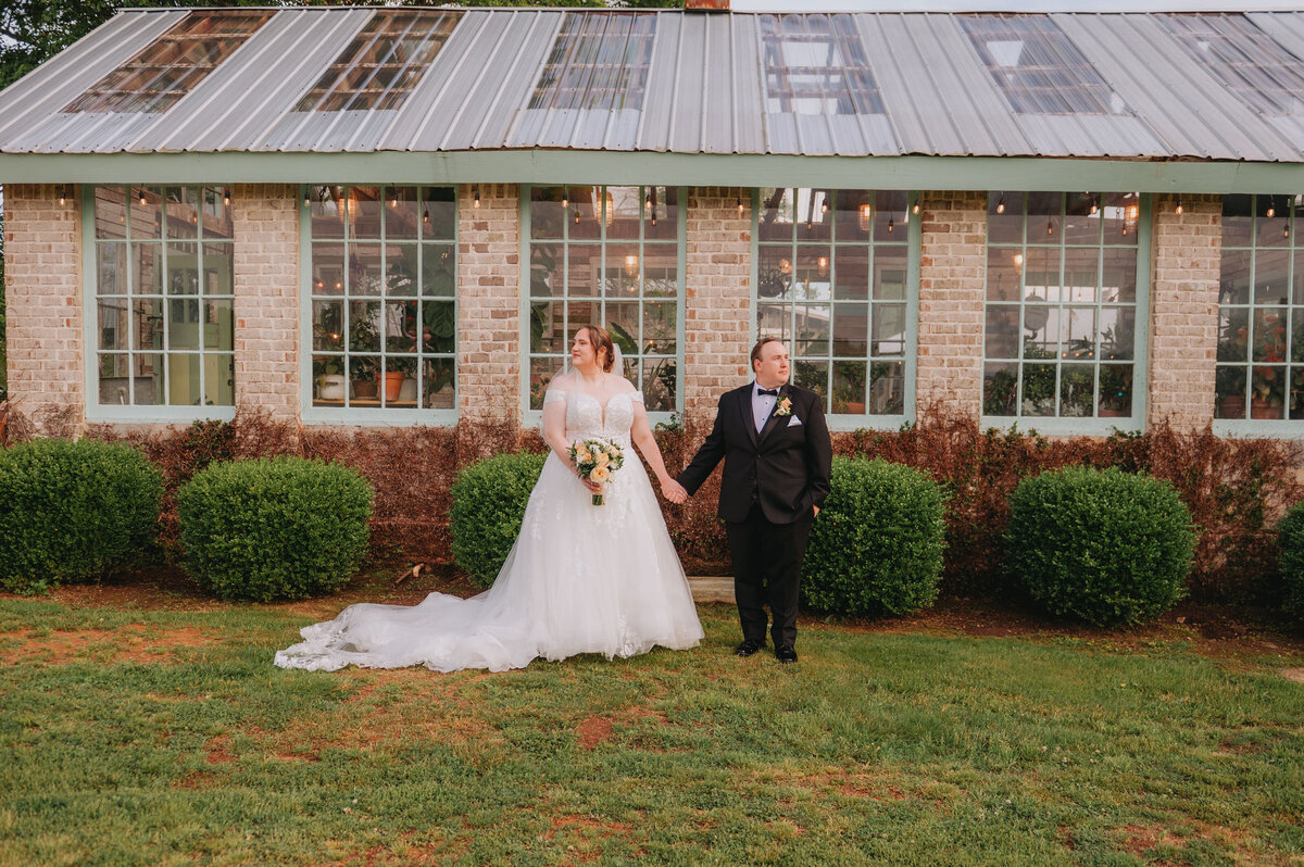 A couple holds hands and looks in opposite directions