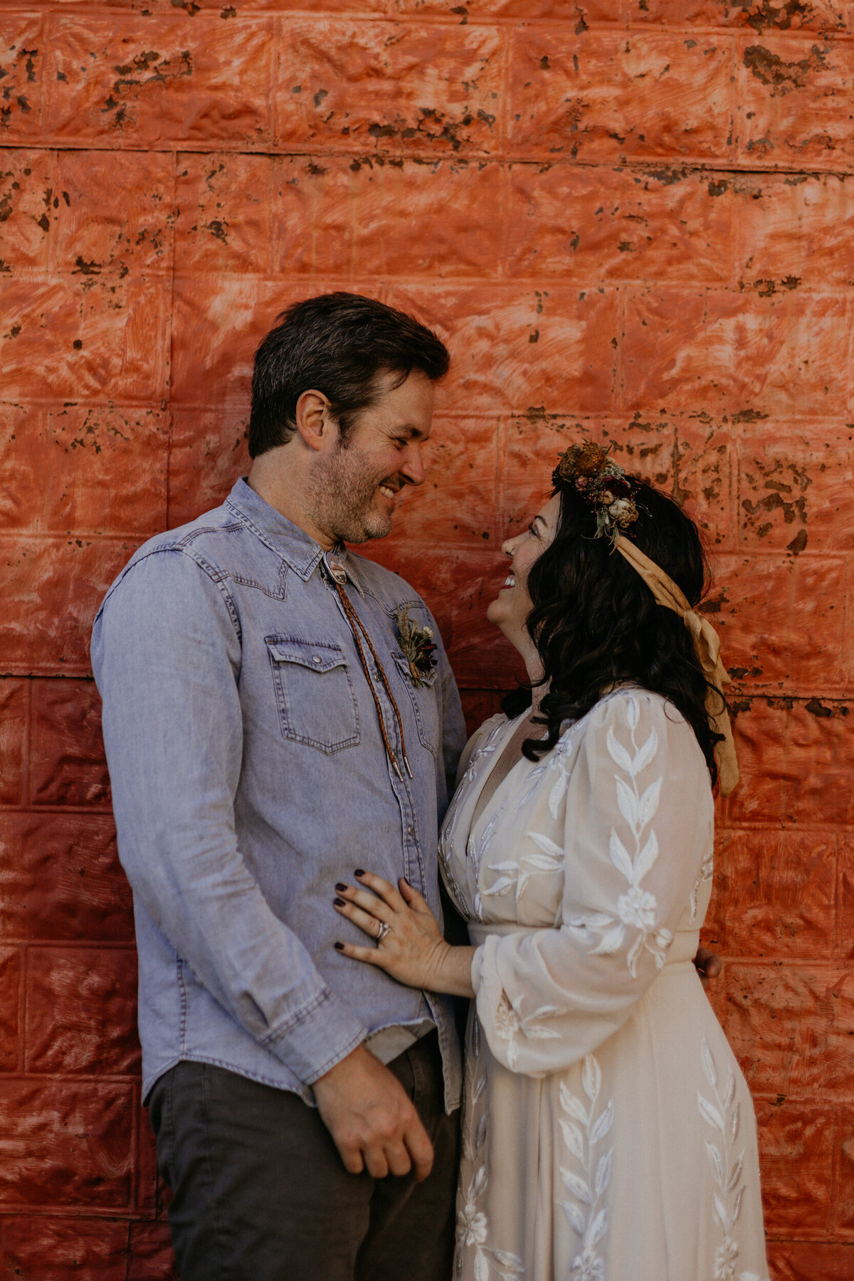 newlyweds standing together in front of a colorful wall in Taos