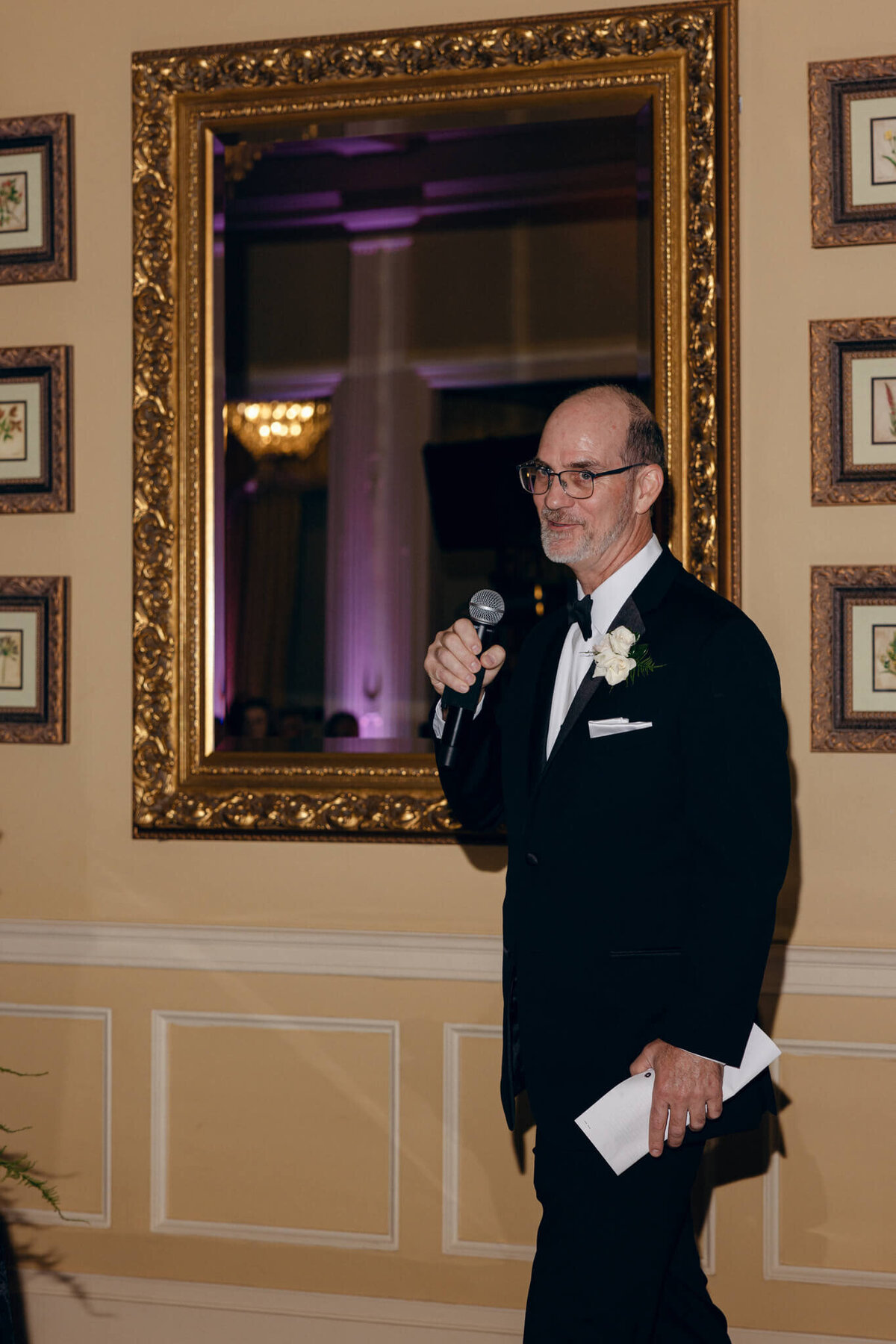 A wedding photo of the brides dad giving a speech during the reception