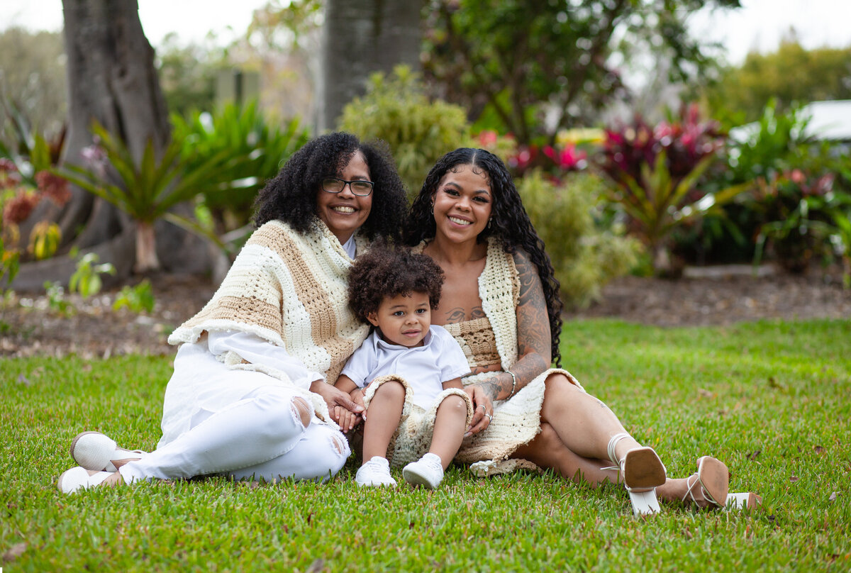 Family sitting in grass smiling at camera