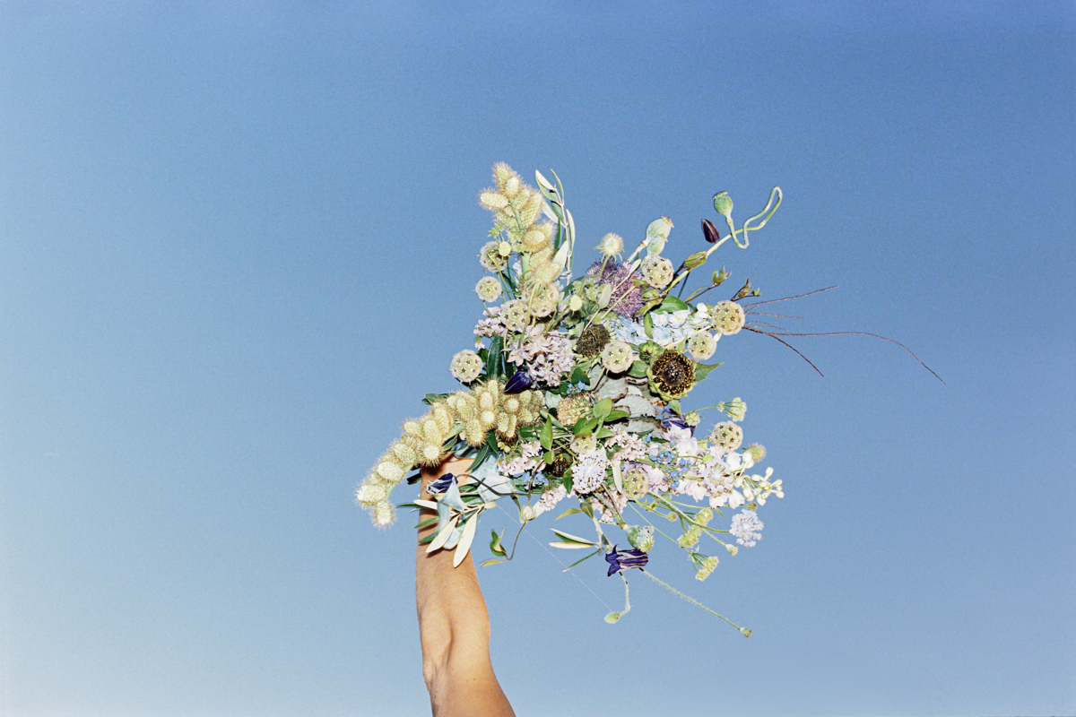 Bride holding bouquet against sky backdrop, captured on film with flash | Editorial wedding portrait by Tess Gearhart Photography