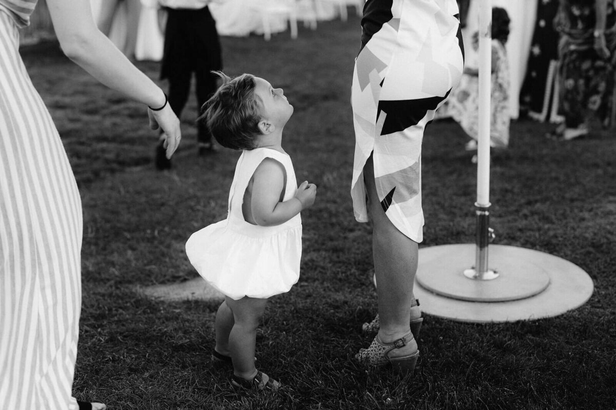 A little girl is looking up at a woman at a wedding in Cape Cod, Osterville, MA.