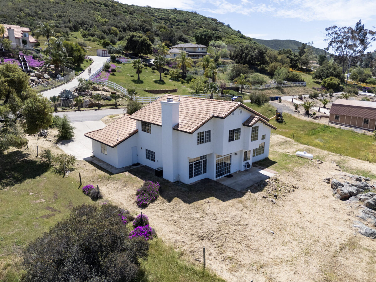 Aerial of back of white home with mountains in the distance.
