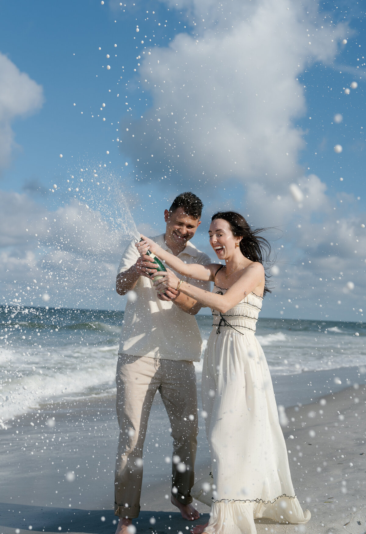Couple popping champagne and laughing by florida engagement photography