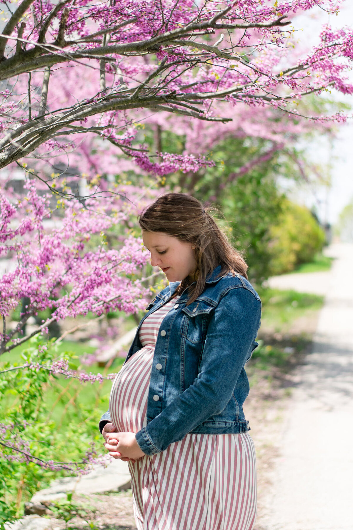 Best maternity photographer in Westwood, MA, Taryn Pratt, who is pregnant and looking at her belly