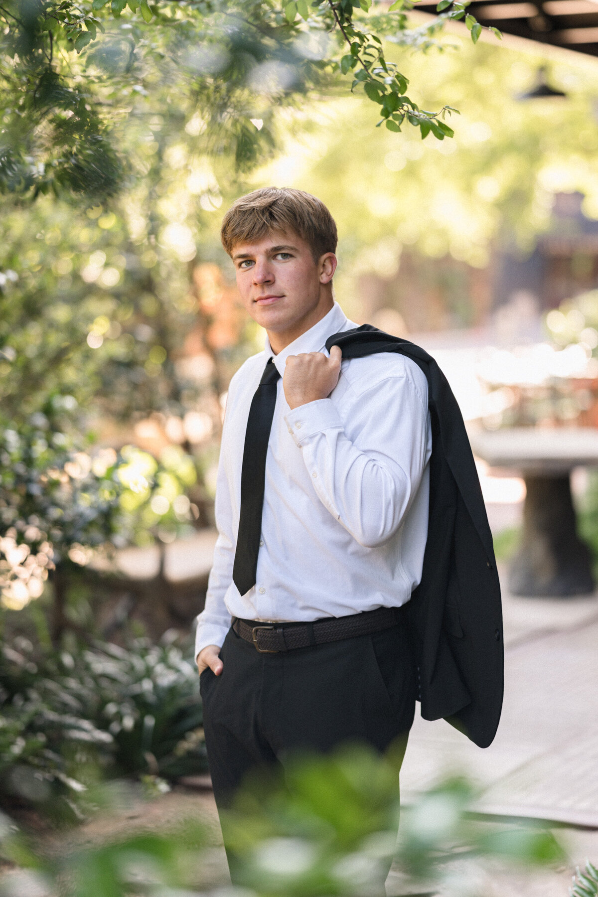 Senior picture of a teenage boy in a suit with his jacket slung over his shoulder at the Pearl in San Antonio. 