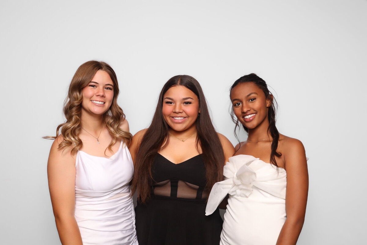 three softball players smile for the photobooth at their softball banquet
