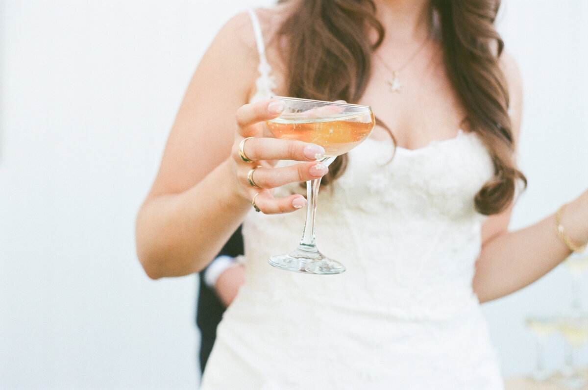 Bride holding a champagne coup on her wedding day film photography