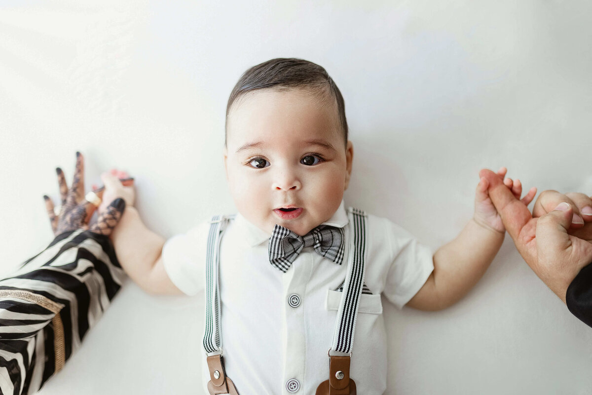 Baby boy held by parents during milestone session -studio baby portraits  Maple Grove