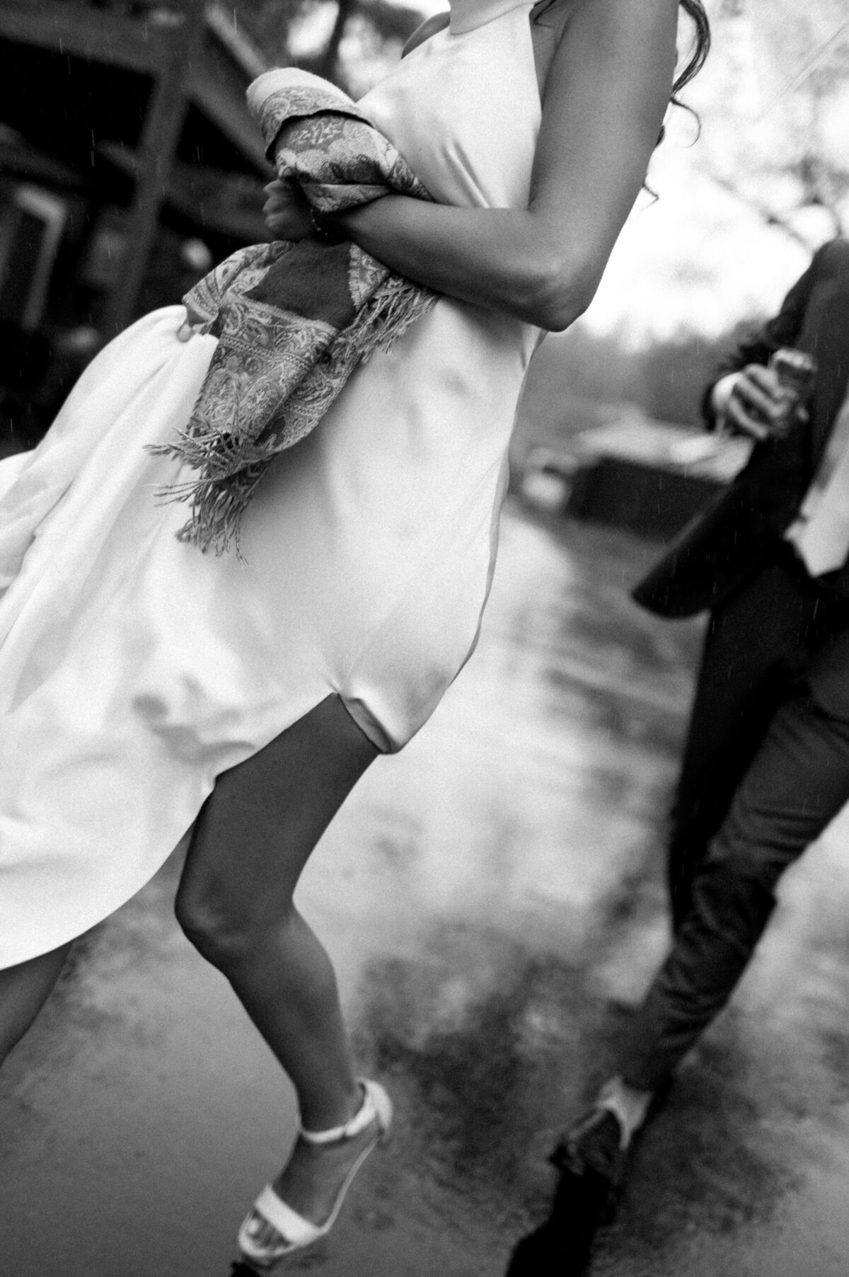 A black and white action shot of the bride and groom dancing. The bride is holding her dress up and you can see a beaded purse.
