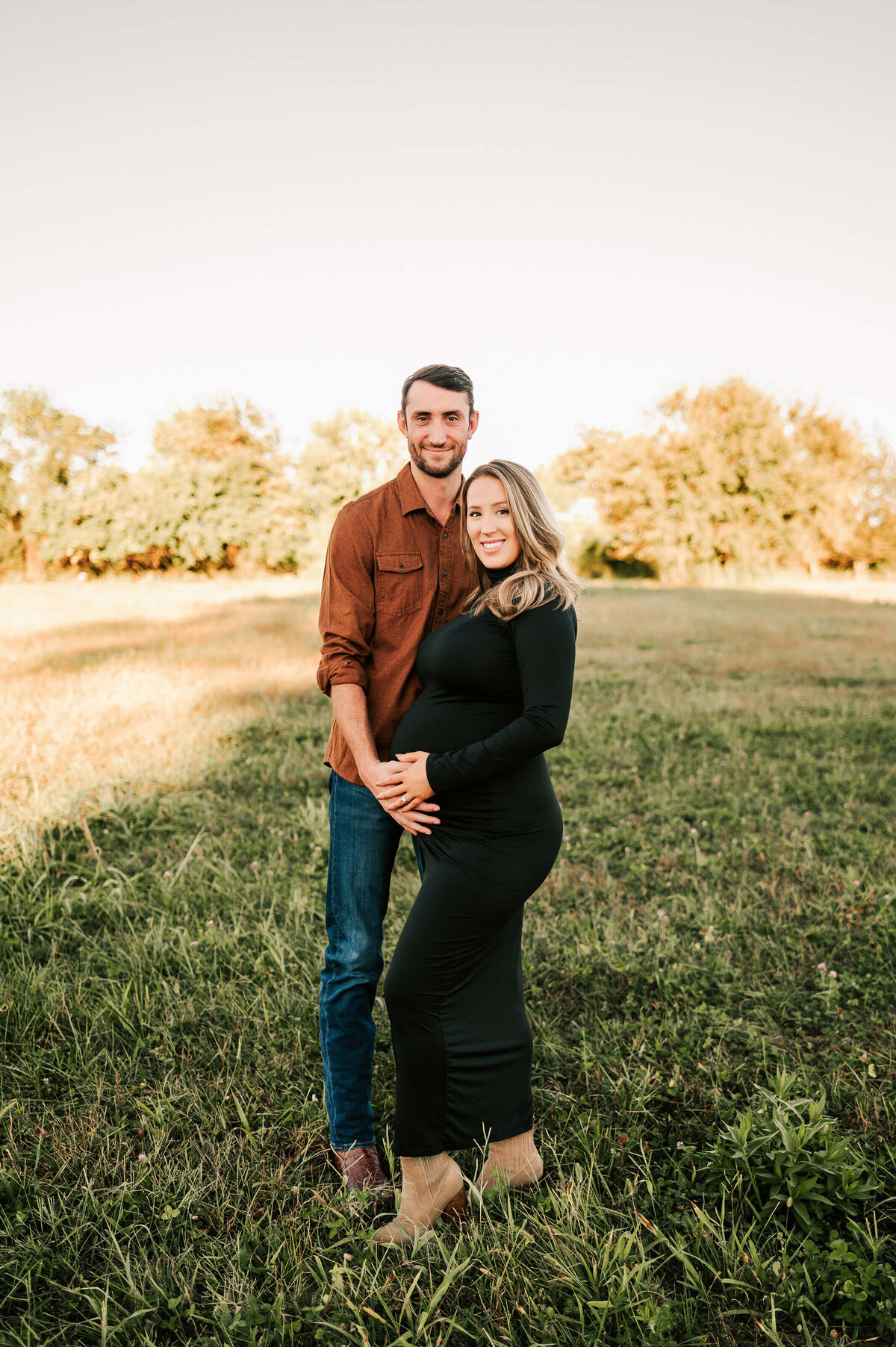 pregnant couple smiling in field during Springfield MO matenrity photography session