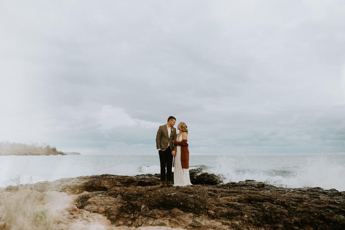 Wedding-couple-Explore-and-Getaway-cozy-On-the-Shoreline-Of-Lake-superior-During-their-Intimate-Elopement-While-the-Large-Fall-Waves-crash