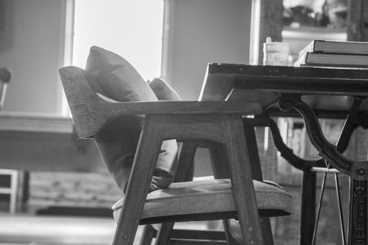 Wooden padded chairs with pillows tucked into wrought iron table black and white photo