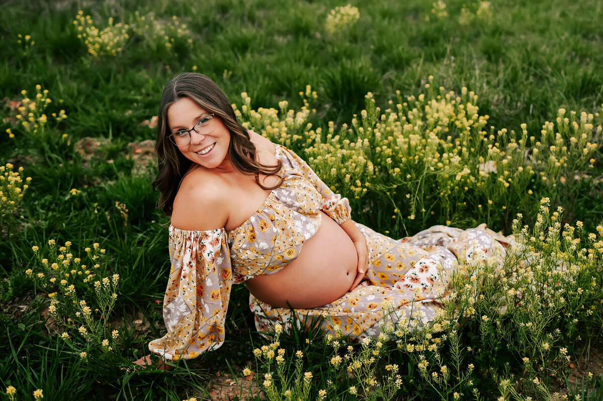 pregnant mom sitting in flower field during Joplin MO maternity photography session