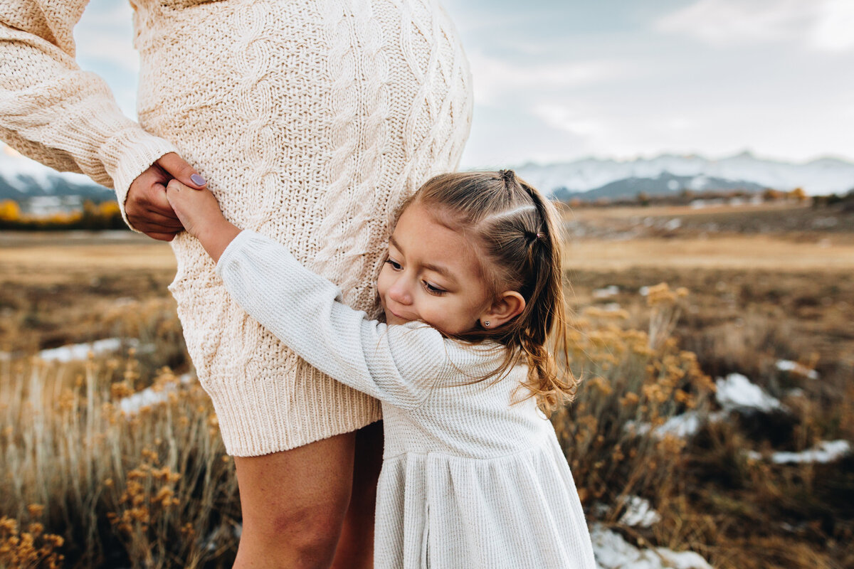 Child hugs her mom at maternity photoshoot in Telluride.
