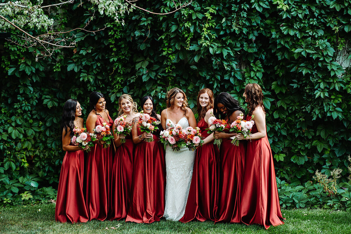Bride with her bridesmaids in rust dresses on the wedding day.