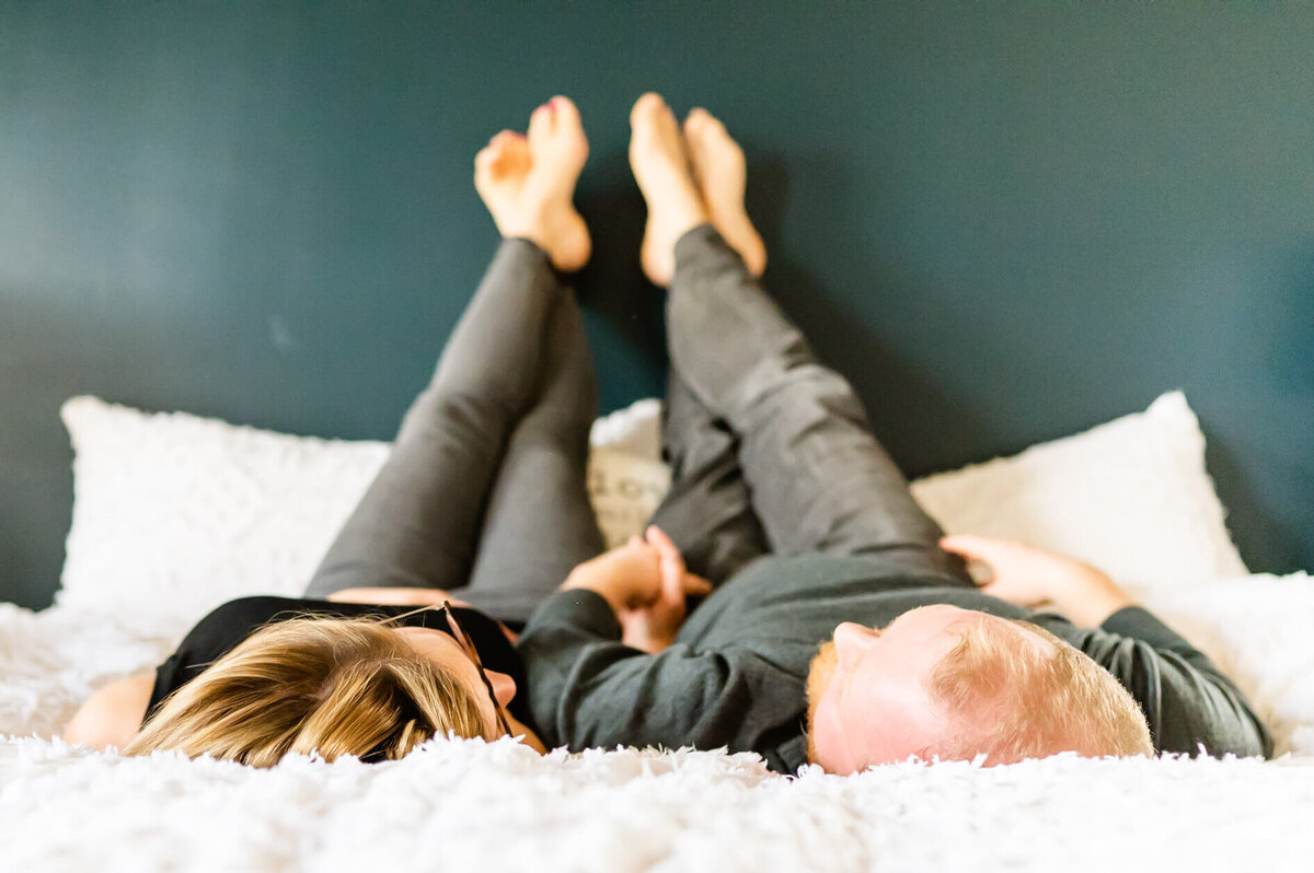 Man and woman laying on bed holding hands during a Chicago couples photography session.