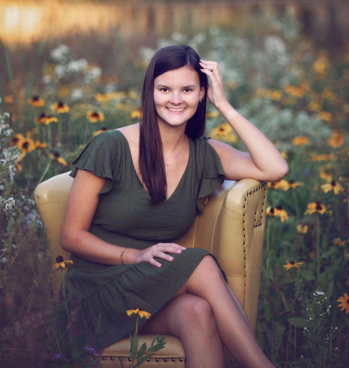 Senior photo of a girl sitting in a yellow chair surrounded by flowers at Asbury Woods in Erie Pa