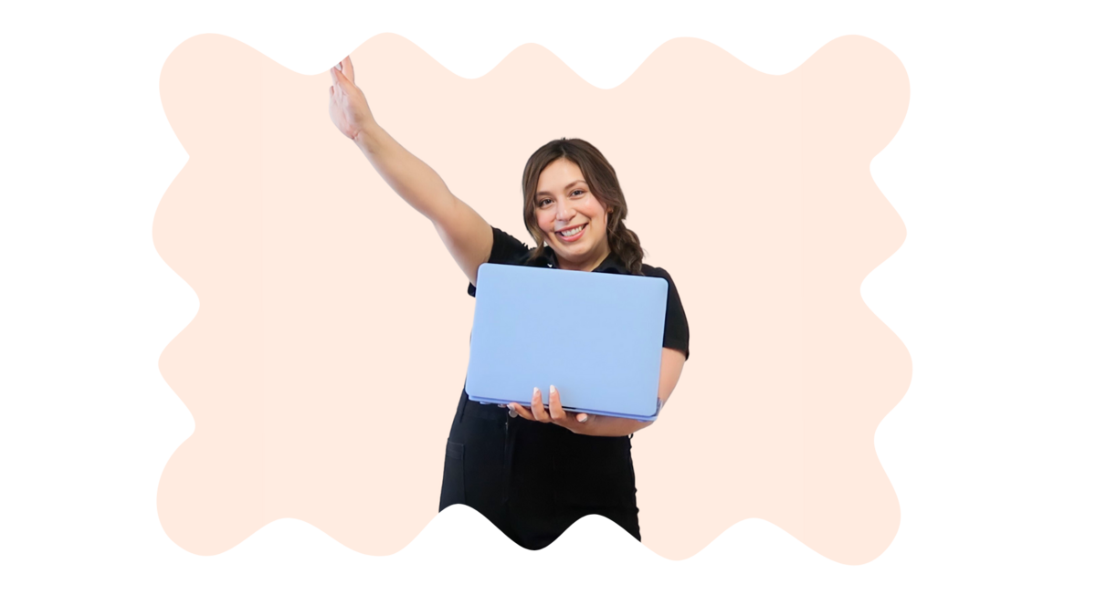 Marie, founder of Kreative Kat, holding a laptop with one arm raised in the air